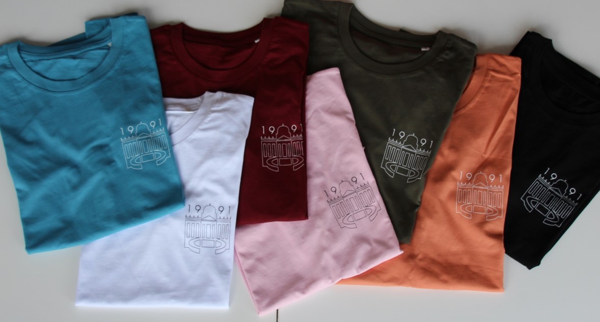 Tshirts- Design D. Abgebildet sind 7 bunte, gefaltete Design D T-shirts  in den  Farben blau, weiß, burgunder, rosa, kaki, orange und schwarz
